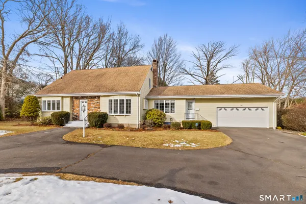 a front view of a house with a yard and large tree