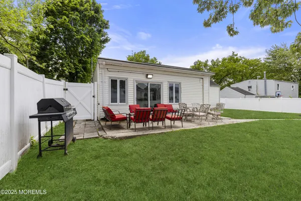 a view of a backyard with table and chairs potted plants and a large tree