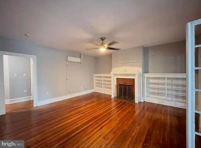 wooden floor fireplace and windows in an empty room