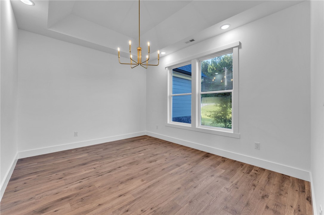 1725 Harris Bridge Road Anderson, SC 29621 - Photo 17 of 33 A refined dining space features a sophisticated chandelier, illuminating warm wood flooring and ample natural light from large windows.
