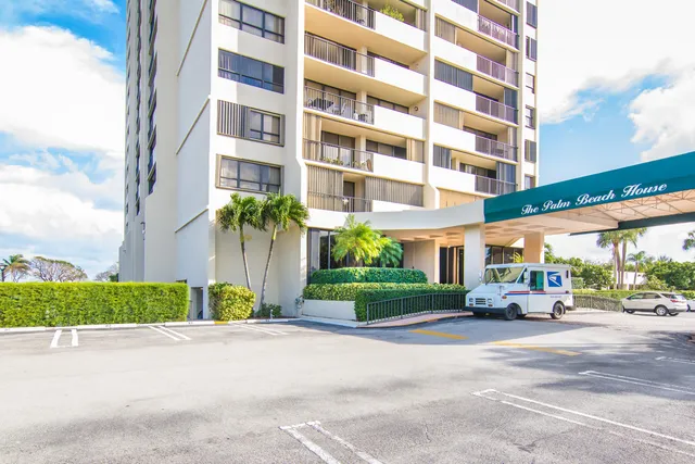 a front view of a building with a garden and parking area