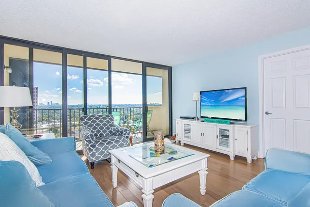 a living room with furniture a flat screen tv and a floor to ceiling window