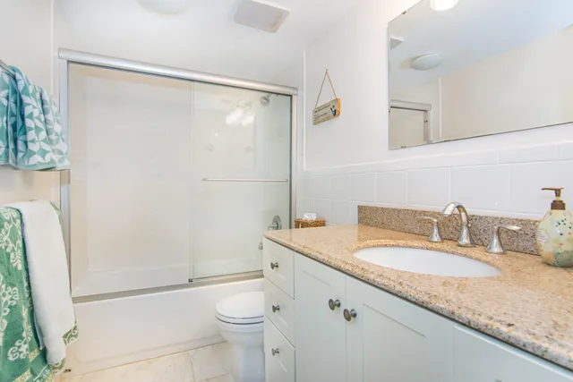 a bathroom with a granite countertop sink toilet and shower
