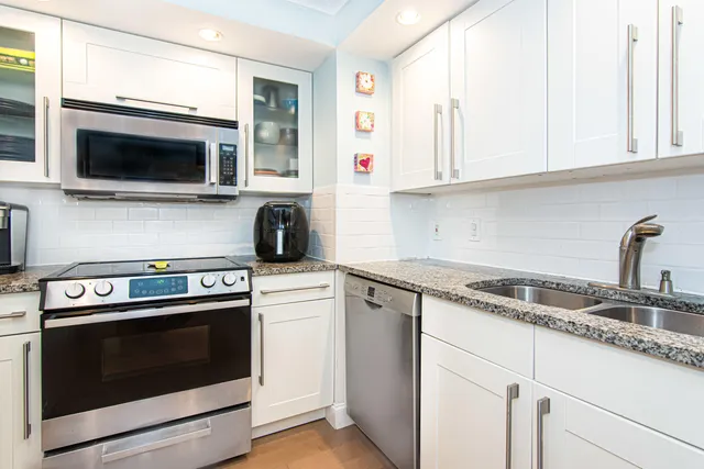 a kitchen with stainless steel appliances granite countertop white cabinets a microwave oven and a sink