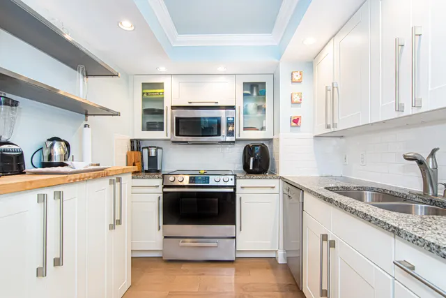 a kitchen with granite countertop white cabinets and white appliances
