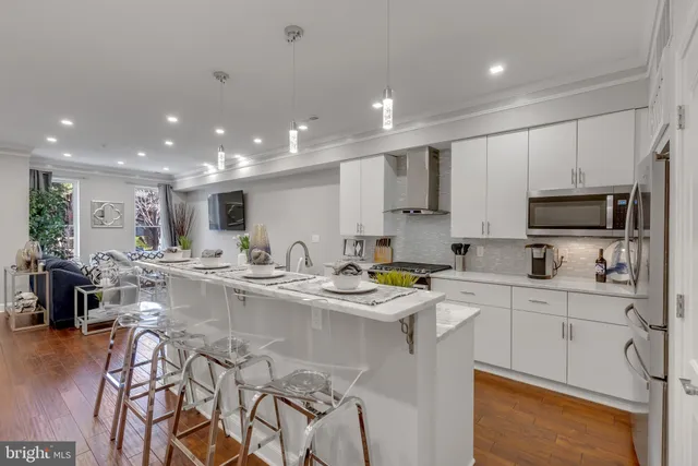 a kitchen with stainless steel appliances granite countertop a stove top oven a sink dishwasher a dining table and chairs with wooden floor