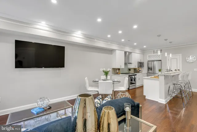 a living room with furniture a flat screen tv and kitchen view