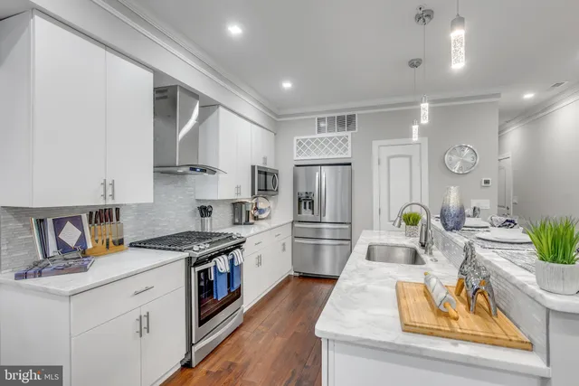 a kitchen with stainless steel appliances granite countertop a refrigerator a stove and a wooden floors