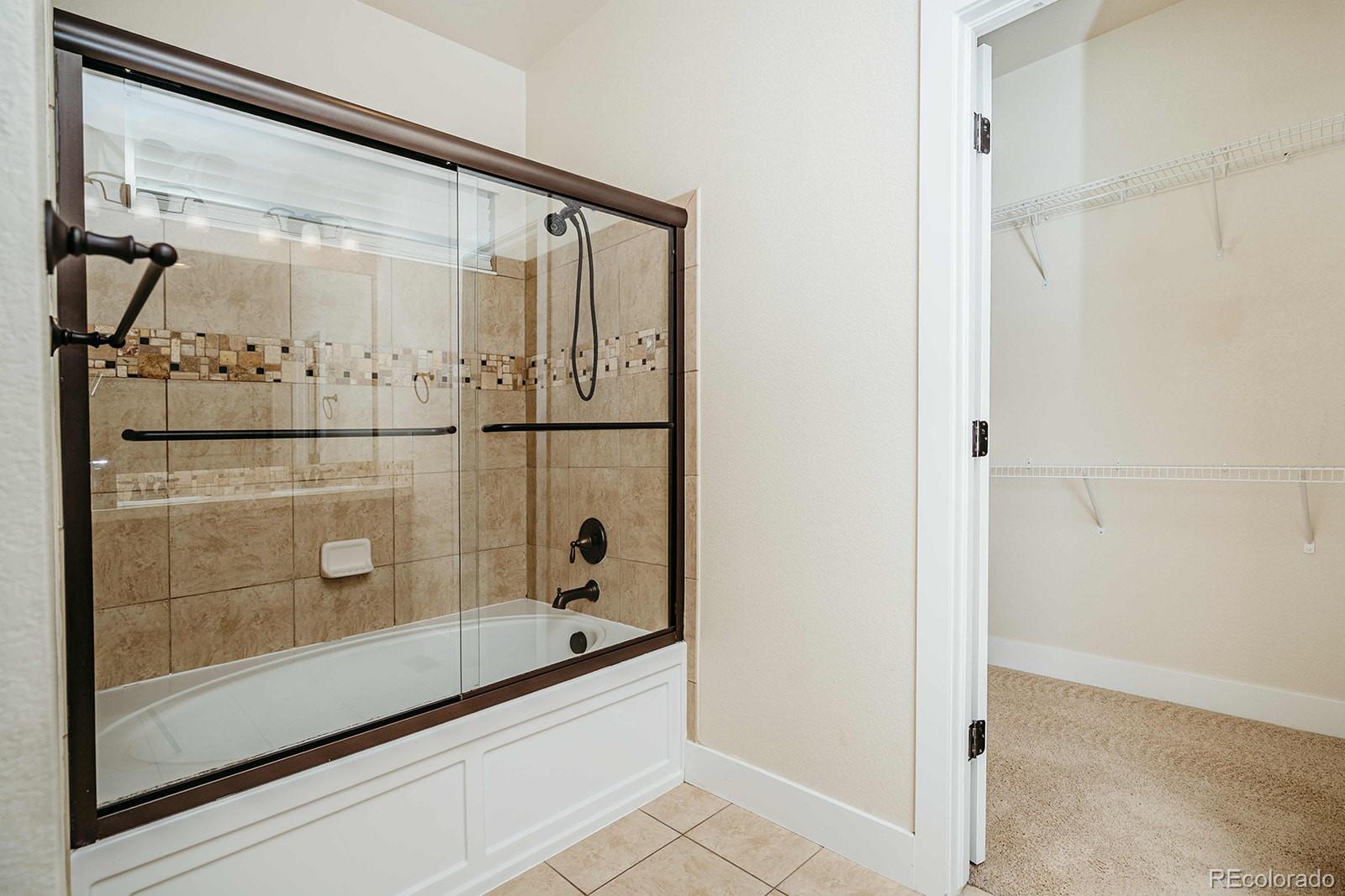10608 Rutledge Street Parker, CO 80134 - Photo 12 of 24 a bathroom with a glass shower door and mirror