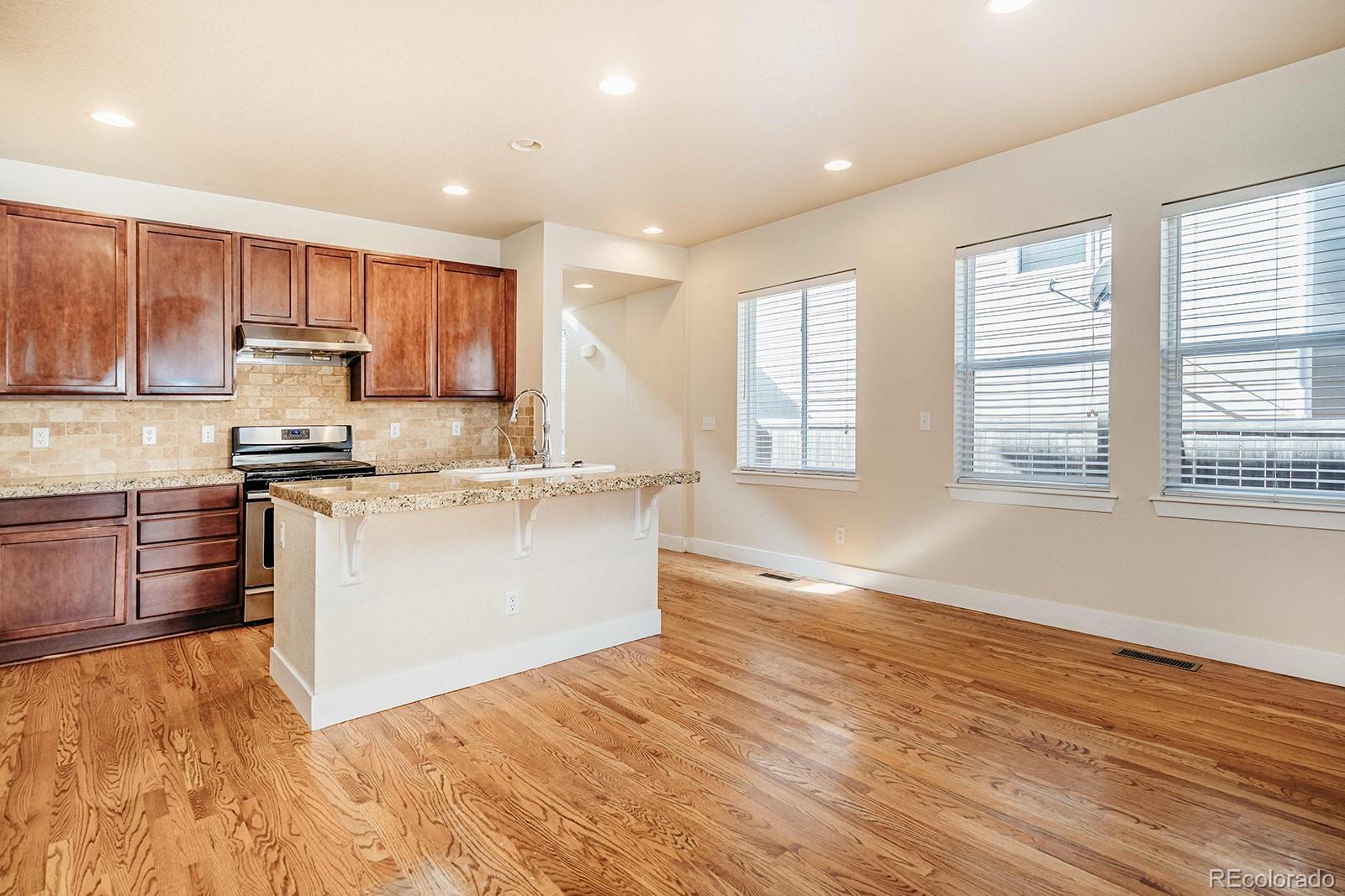 10608 Rutledge Street Parker, CO 80134 - Photo 6 of 24 a kitchen with granite countertop a stove a sink and a refrigerator