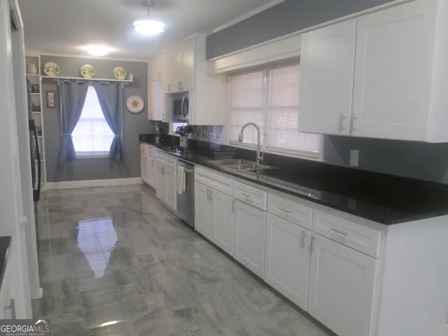 a kitchen with granite countertop a sink stainless steel appliances and cabinets