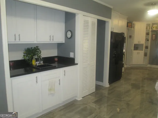 a kitchen with granite countertop white cabinets and refrigerator