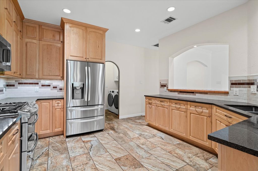 37 Pillow Road Austin, TX 78745 - Photo 7 of 18 Streamlined culinary space featuring light wood cabinetry, sleek black countertops, and contemporary appliances.