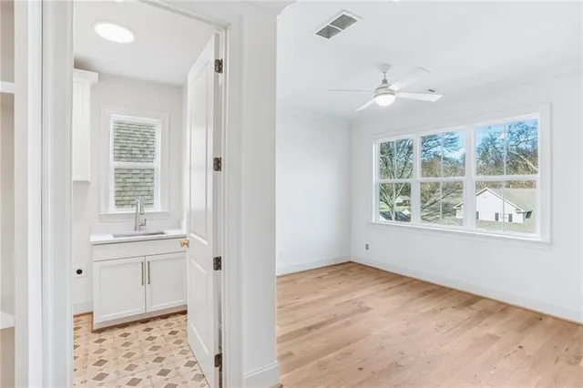 an empty room with wooden floor cabinet and windows