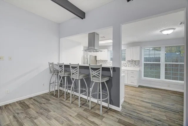 a dining room with furniture wooden floor a potted plant and a chandelier