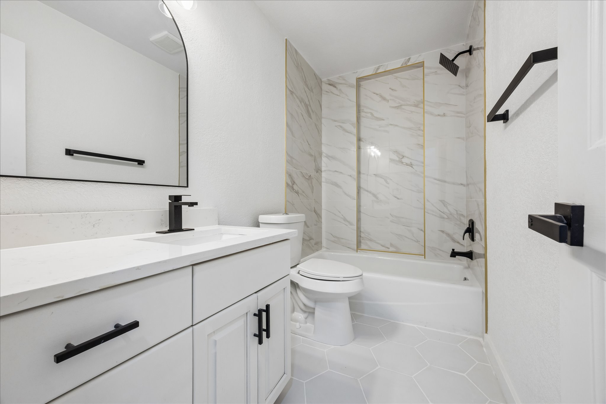 1706 Davis Street Taylor, TX 76574 - Photo 13 of 18 Modern guest bathroom featuring sleek vanity with solid surface countertop and a tiled shower with gold accents.