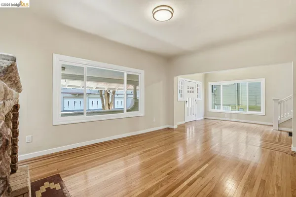 a view of an empty room with a window and wooden floor
