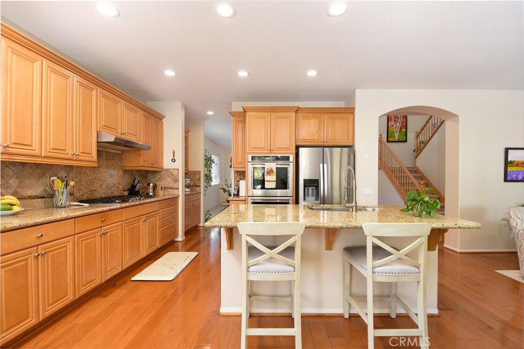 41686 Monterey Place Temecula, CA 92591 - Photo 14 of 51 a kitchen with stainless steel appliances granite countertop a stove a sink dishwasher and white cabinets with wooden floor