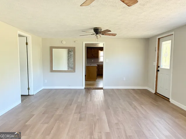 an empty room with wooden floor cabinet and windows