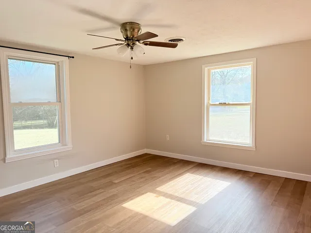 a view of an empty room with wooden floor and a window