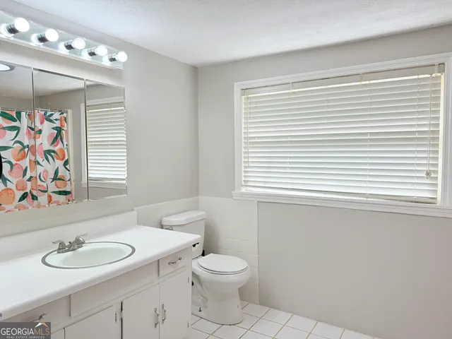 a bathroom with a toilet a sink a mirror and a window