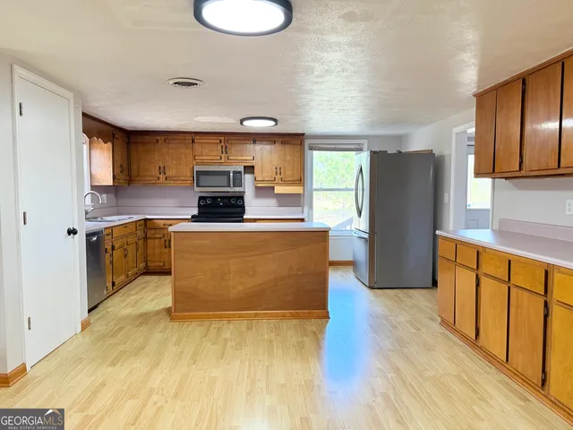 a large kitchen with stainless steel appliances granite countertop a refrigerator a stove top oven a sink and dishwasher with wooden floor