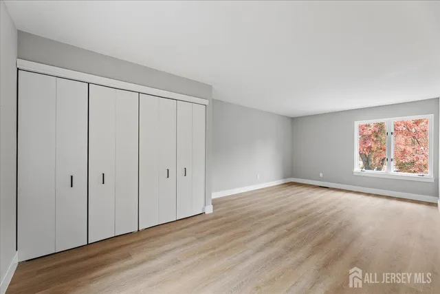 a view of an empty room with wooden floor and window