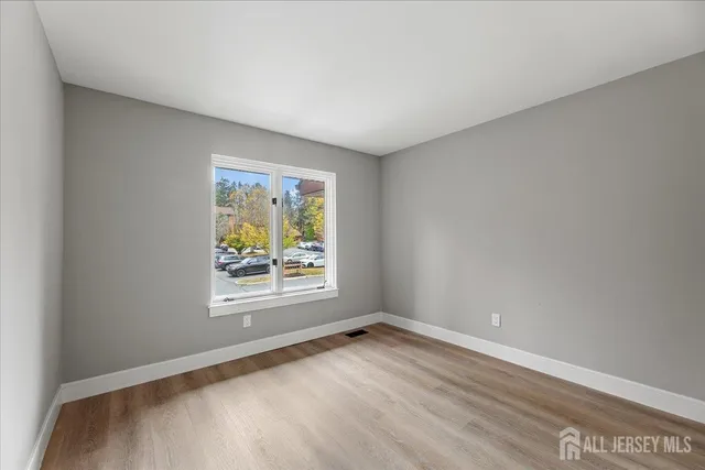 a view of an empty room with wooden floor and entryway