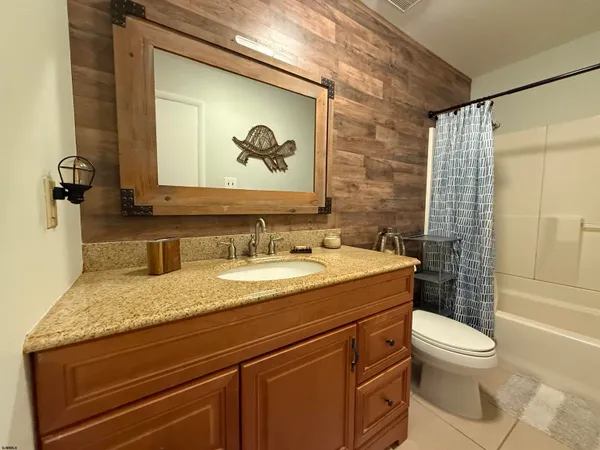 a bathroom with a granite countertop sink a toilet and a shower