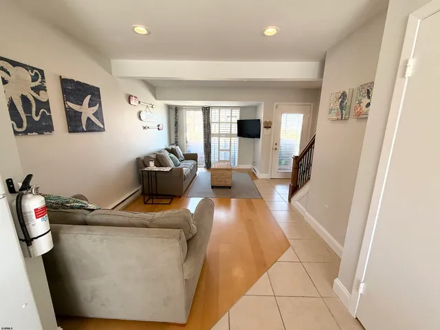 a hallway with a view of living room with furniture and a window