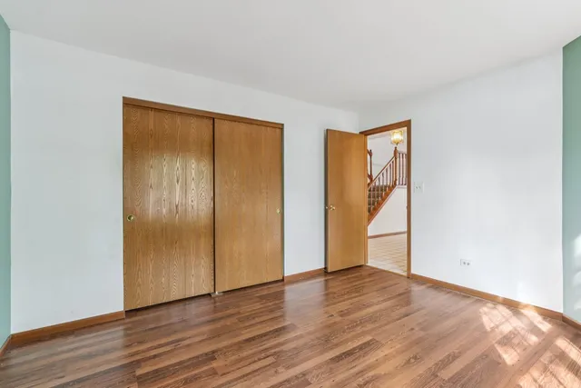 a view of an empty room with wooden floor and closet