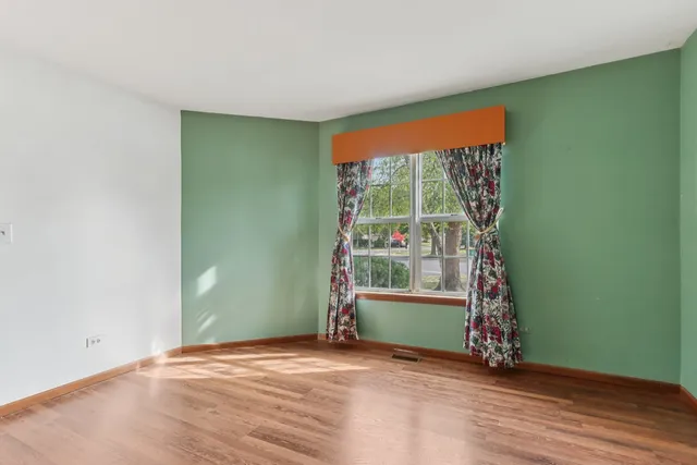 a view of an empty room with window wooden floor and front door