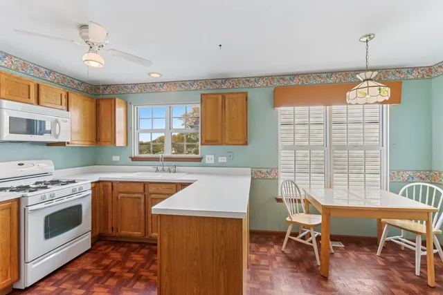 a kitchen with a stove a sink dishwasher a dining table and chairs with wooden floor