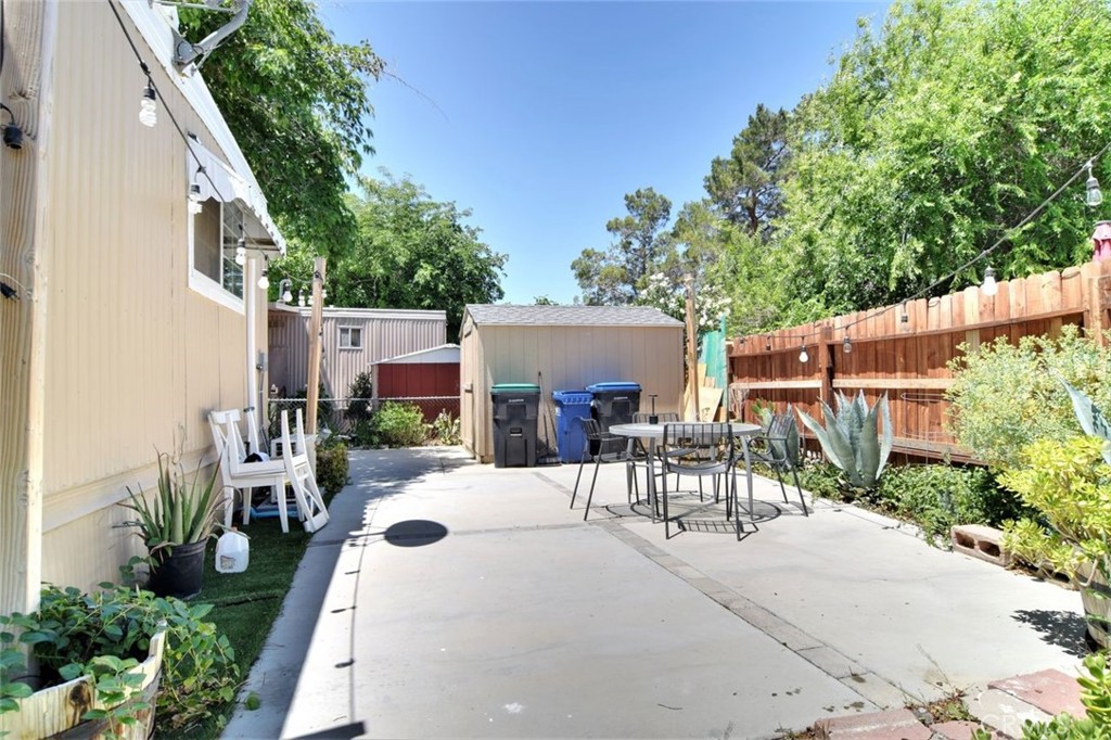 3255 East Avenue R, Unit 98 Littlerock, CA 92550 - Photo 11 of 12 a view of a patio with table and chairs potted plants and large tree