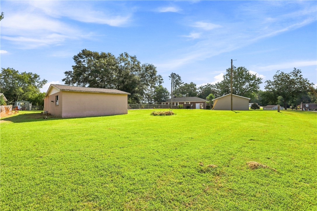 205 Timms Road Piedmont, SC 29673 - Photo 26 of 36 A spacious grassy lawn stretches across the property with several outbuildings under a clear sky.