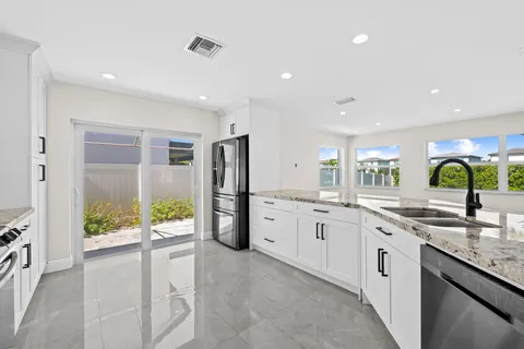 a kitchen with stainless steel appliances granite countertop a refrigerator a stove top oven a sink and dishwasher