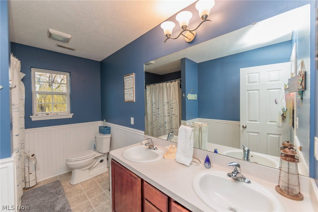 32883 Walnut Drive Avon, OH 44011 - Photo 23 of 34 Bathroom with tile flooring, a textured ceiling, toilet, and dual bowl vanity