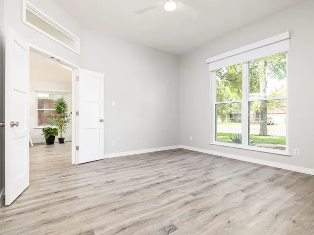 a view of an empty room with wooden floor and a window