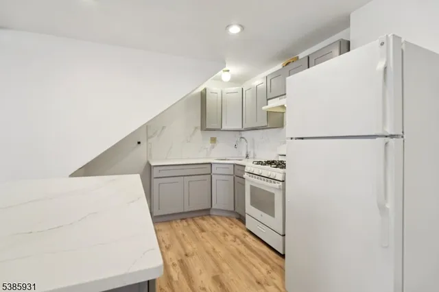 a kitchen with a sink a refrigerator and white cabinets