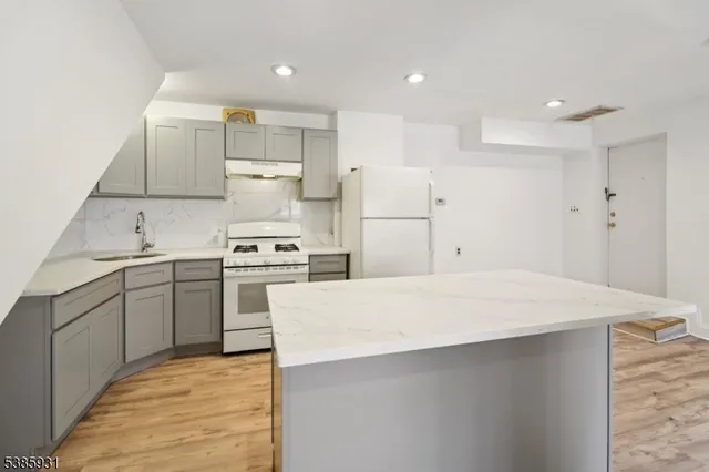a kitchen with a sink a stove a refrigerator and white cabinets