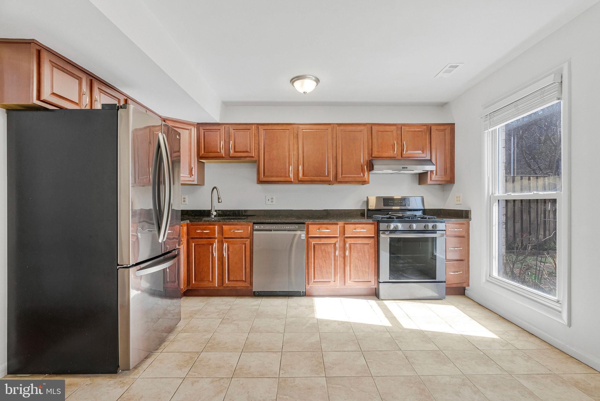 2131 Ferguson Place Herndon, VA 20170 - Photo 7 of 27 a kitchen with granite countertop a refrigerator and a stove top oven