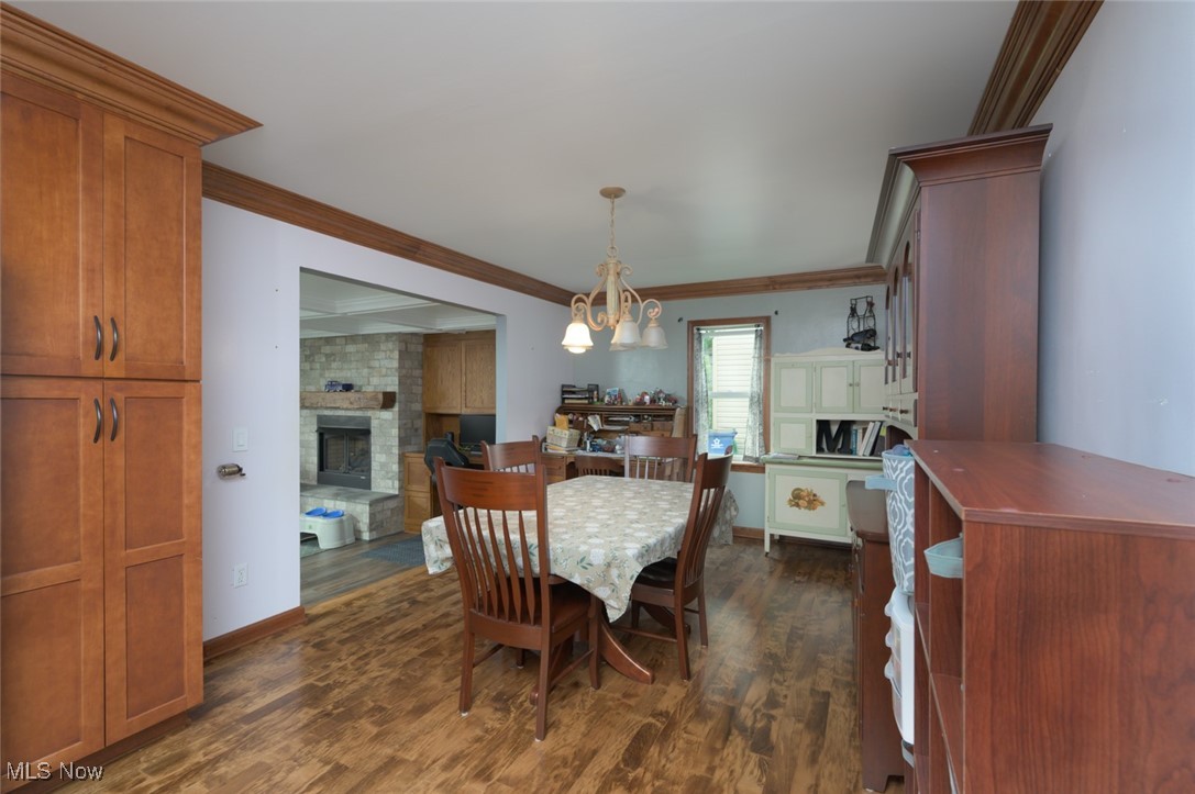 3234 Bell Wick Road Hubbard, OH 44425 - Photo 16 of 27 Dining space featuring dark wood-style flooring, a chandelier, ornamental molding, and a fireplace
