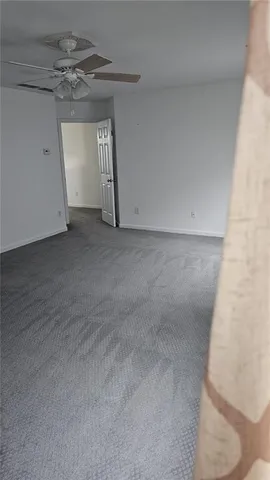 an empty room with windows and ceiling fan