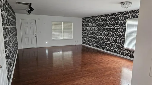a view of empty room with wooden floor and fan