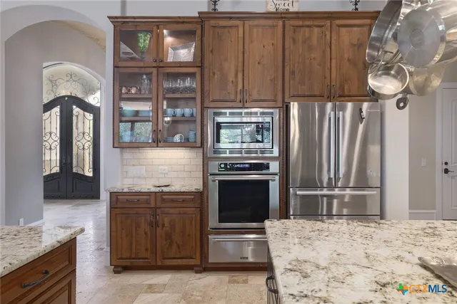 a kitchen with stainless steel appliances granite countertop a refrigerator and a stove top oven