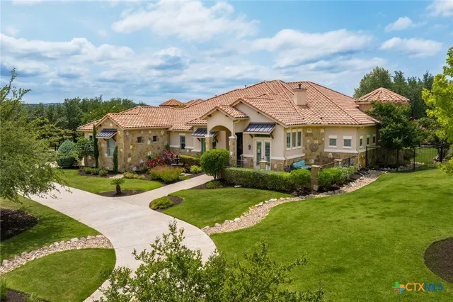 a view of a white house with a big yard and potted plants