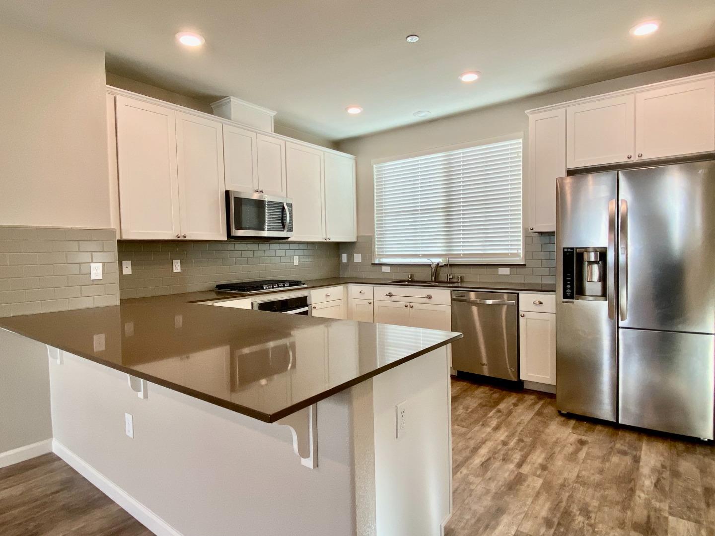 a kitchen with stainless steel appliances granite countertop a refrigerator a sink a stove a microwave and cabinets