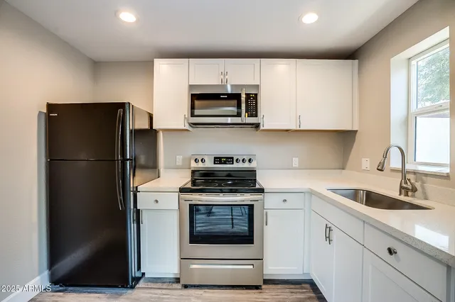 an empty room with wooden floor a ceiling fan and windows