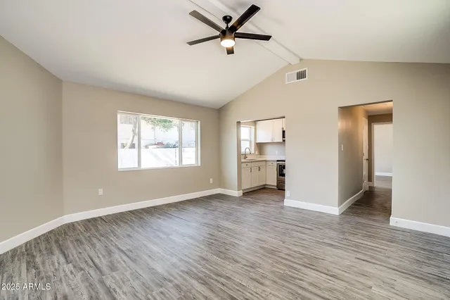 a view of a kitchen and an empty room with wooden floor