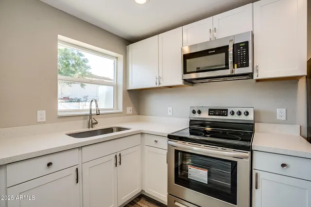 a kitchen with cabinets appliances a sink and a window